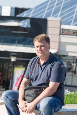 Yorgun bir yetişkin adam alışveriş yaptıktan sonra parkta bir bankta dinlenmek için oturdu..