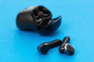 Modern kablosuz kulaklıklar mavi arkaplanda şarj ediliyor.