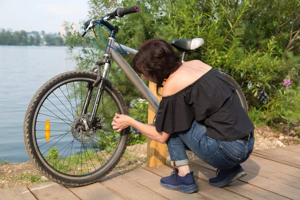 자전거를 여자가 바퀴의 타이어에 뚜껑을 뒤틀고 — 스톡 사진