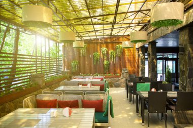 Verandada yeşil duvarlarla süslenmiş güzel bir açık hava restoranı..