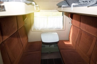 Demiryolu treninin kompartımanında sırtı yüksek yumuşak koltuklar..