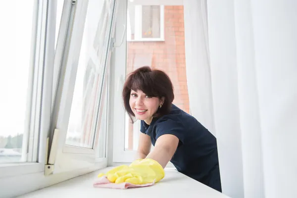 Sarı Eldivenli Esmer Bir Kadın Gülümseyerek Pencerenin Kenarındaki Tozu Siliyor — Stok fotoğraf