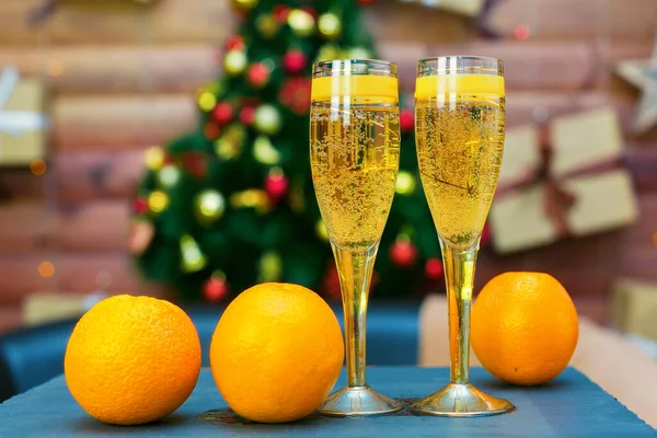 Två Glas Champagne Med Ljusa Saftiga Apelsiner Bakgrunden Dekorerad Julgran — Stockfoto