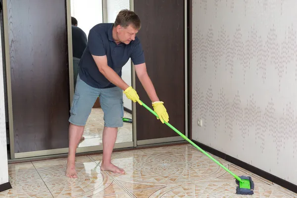 미소를 남자가 아파트 바닥을 만들어 아내가 청소하는 — 스톡 사진