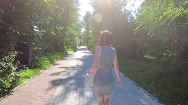 Yazlık elbiseli mutlu esmer kadın dönüyor ve gülüyor. Yavaş çekim.