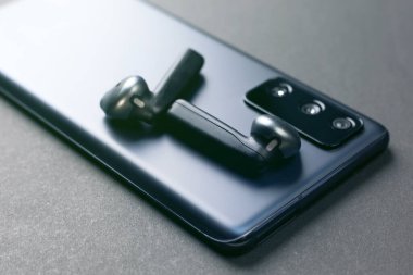 Telefon kılıfındaki kablosuz siyah kulaklıklar sevilen birine konsept bir hediye..