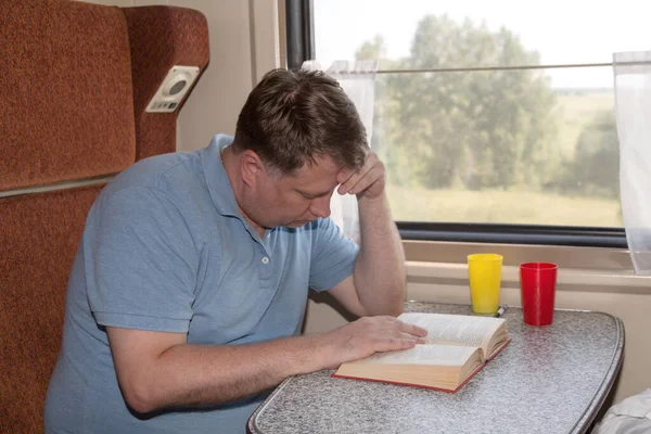 Egy Fáradt Felnőtt Férfi Vonatfülkéje Egy Asztalnál Alszik Könyvvel Kezében — Stock Fotó