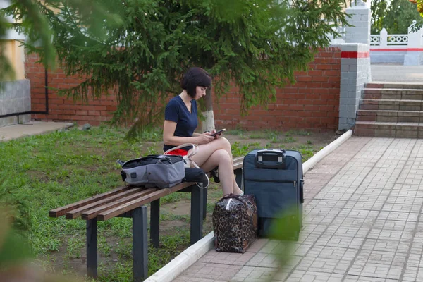 Happy Brunette Woman Sitting Bench Train Station Lot Bags Suitcase — стоковое фото