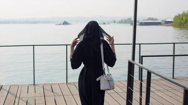 一位身穿民族服装的穆斯林妇女走在通向河边的一座木桥上 后视镜 — 图库照片
