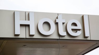 Gri yağmurlu gökyüzünün arka planına karşı binanın girişinin üstündeki yazıt otel..