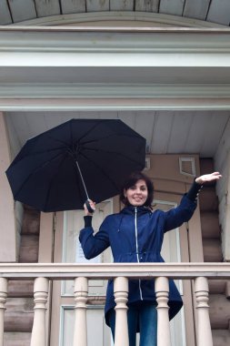 Elinde siyah şemsiyesi olan mutlu bir kadın. Eski ahşap bina..