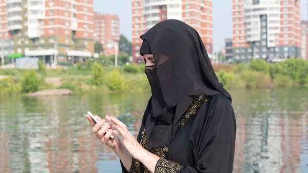 Een Moslimvrouw Nationale Kleren Met Haar Gezicht Bedekt Met Telefoon — Stockfoto