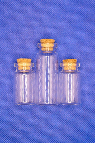 Three empty glass bottles with stoppers for storing small parts.,