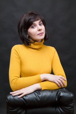 Sarı kazaklı kadın, ofis müdürü deri sandalyenin yanında..