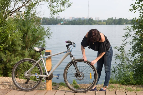 여자가 자전거를 타다가 부러진 바퀴를 확인하는 — 스톡 사진