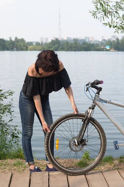 여자가 자전거를 타다가 부러진 바퀴를 확인하다 — 스톡 사진