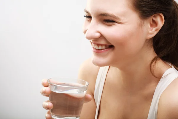 Усміхнена молода жінка зі склянкою води — стокове фото