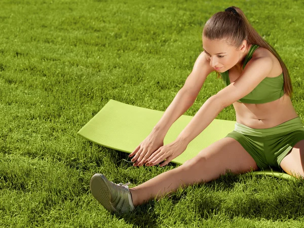 Una bella donna sportiva che fa esercizio di stretching contro natur — Foto Stock