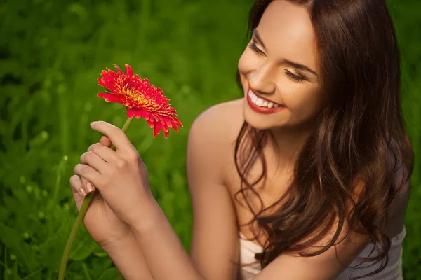 Mooi meisje met gerbera bloem genieten van natuur. — Stockfoto