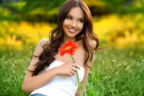 Menina bonita com flor de Gerbera apreciando a natureza . — Fotografia de Stock
