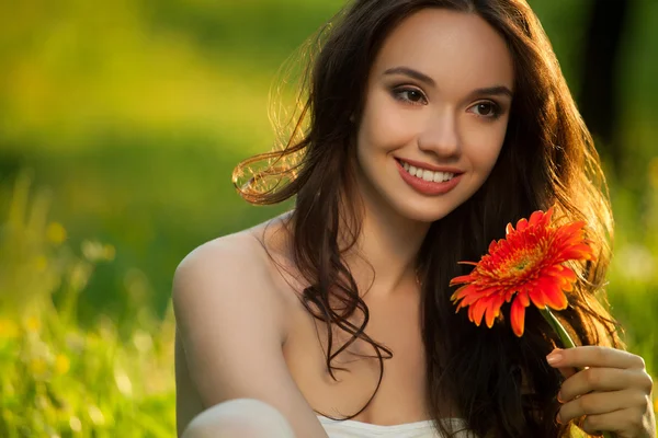 Gyönyörű nő élvezi természet gerbera virággal. — Stock Fotó