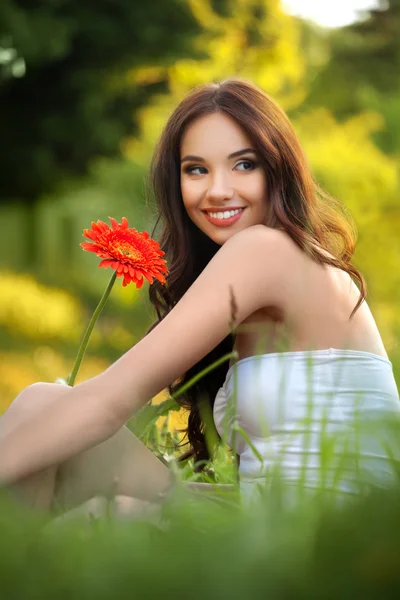 Mulher bonita com flor de Gerbera apreciando a natureza . — Fotografia de Stock