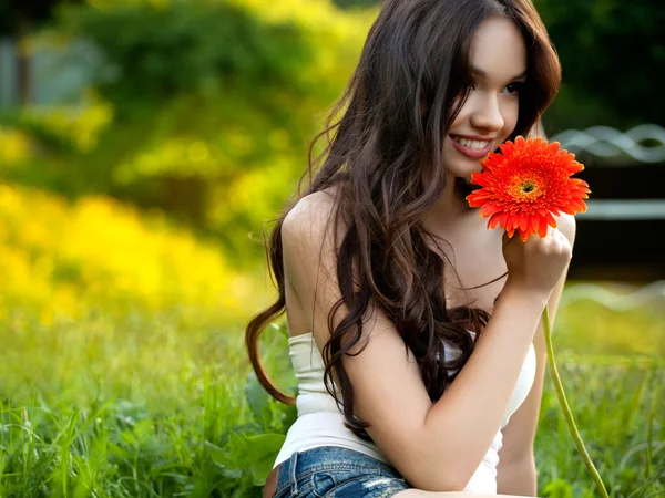 Krásná žena s květem gerbera užívat přírodu. — Stock fotografie