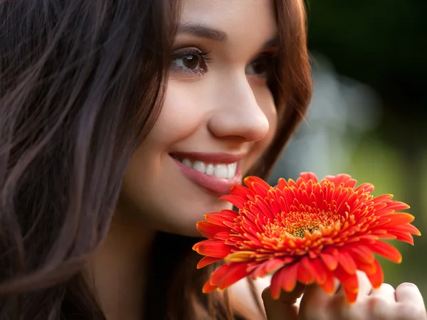 Mooie vrouw met gerbera bloem genieten van natuur. — Stockfoto