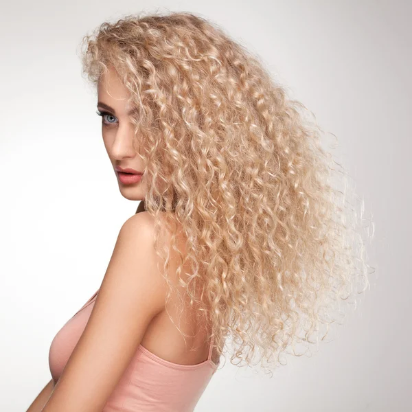 Blond vlasy. krásná žena s dlouhými kudrnatými vlasy. — Stock fotografie