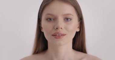 Güzel surat. Gri arka planda doğal güzelliği olan büyüleyici genç bir kadının portresi. Moda modeli pürüzsüz bir ten, mavi gözler ve dolgun dudaklar..