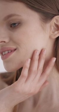 Güzellik yüz bakımı. Beyaz tenli, taze tenli, gri arka planlı, duygusal bir şekilde stüdyoda poz veren genç bir kadın. Cilt bakımını, güzelliği ve kaplıcayı.