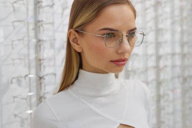 Gözlükçüdeki Müşteri Kadın Portresi. Blonde Moda Modeli Şık Optik Gözlük Giyiyor Arka planda Gözlüklü Vitrinde Duruyor