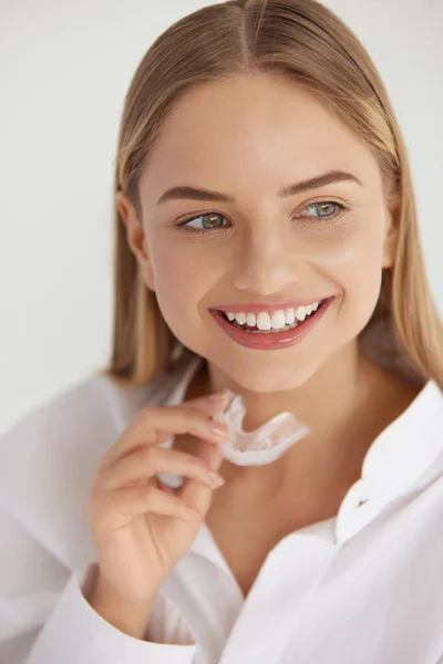 Teeth whitening. Woman with White Smile, Healthy Straight Teeth Using Clear Removable Braces, Invisible Teeth Tray. Portrait of Girl Doing Dental Beauty Treatment