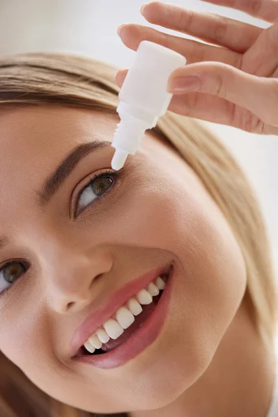 Woman With Eye Drops. Closeup Of Girl Applying Eye Drops In Eyes. Cheerful Blonde Woman Putting Eye Drops at her Eyes while Having Healthy Procedures. Vision Concept