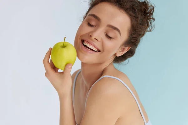 緑のリンゴを持つ女性 新鮮な緑のリンゴを持ちながら目を閉じて笑顔の若い女性 美しいです女性とともに自然の白い笑顔ポージングでスタジオで熟した有機果物で手 — ストック写真