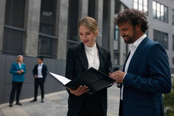 Serious Business Couple Outdoors Examining Documents Attractive Businessman Businesswoman Standing — стокове фото