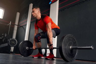 Athletic Man Making Weightlifting or Powerlifting, Working on Arms and Chest Muscles. Muscular Bodybuilder Exercising with Heavy Barbell at Modern Gym 