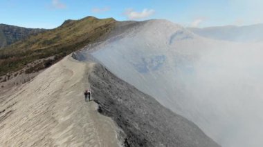 Couple of Hikers Walking on Ridge of Mount Gunung Bromo Volcano in East Java, Indonesia. Mount Bromo is Active Volcano with Crater. Concept of Adventure and Travelling
