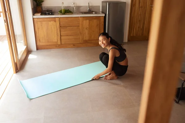 Workout At Home. Woman Rolling Yoga Mat Before Exercising. Female In Sportswear Folding Fitness Rug After Completing Daily Sport Routine