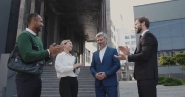 İş ortakları başarılı bir anlaşmadan sonra birbirlerini alkışladılar. Takım arkadaşları Ofis Binası 'nın yakınındaki caddede duruyorlar. İnsanlar Mutlu Hissediyor 