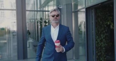 Caddede Yürüyen Kıdemli İşadamı. İş adamı kahve molası vermek için kahve tutuyor. Olgun Adam Ofis Binası 'nın yakınında sıcak içkinin tadını çıkarıyor. İş ve Yaşam Tarzı Konsepti 