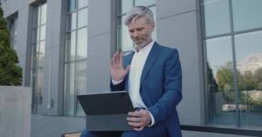 Yakışıklı İşadamı Tablet 'inde Video Sohbeti ile Konuşuyor. Gri Saçlı Yönetici Caddede video görüşmesi yaparken kendine güler yüzlü. Video Çağrısı Konsepti 