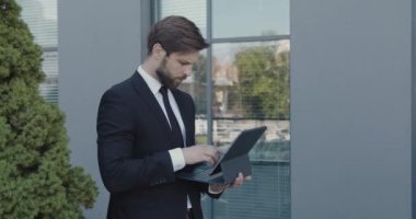 Sokaktaki İş Adamı ve Modern Şehir Ofisi 'nin yanındaki dizüstü bilgisayarla çalışıyor. Dışarıdaki Erkek E- postalarını Kontrol Ediyor. Odaklanmış Girişimci Tarayıcı Daktilo 