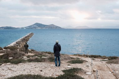Bulutlu perde manzaralı Yunan adasına bakan adam
