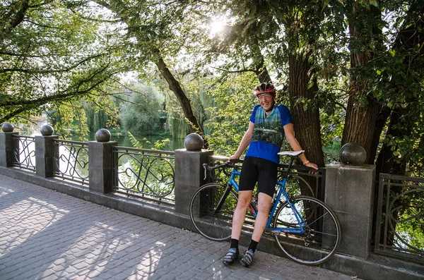 Mannen i uniform skrattar nära floden med racing cykel — Stockfoto