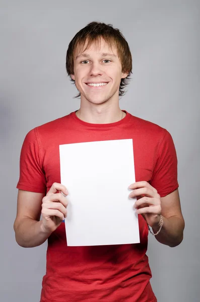 Man in red shirt smiles and shows a white card — Stock Photo, Image