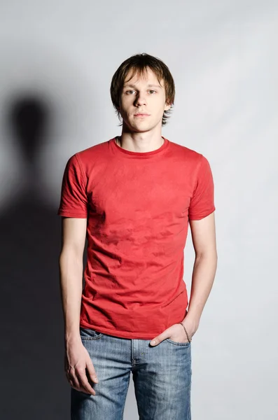 Man in red shirt looks at camera with hand in pocket — Stock Photo, Image