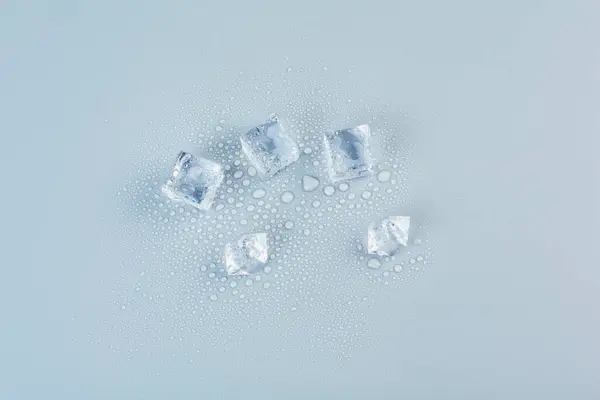 Five ice cubes on a gray background in the center — Stock fotografie
