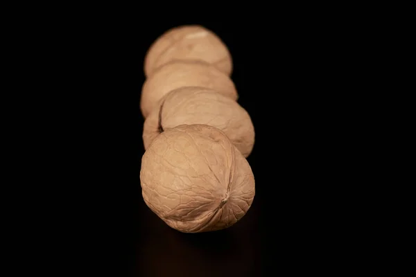 Walnuts lined up one after another on a black background — стоковое фото