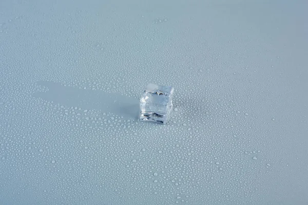 One ice cube on a gray background behind it is left a trail of sliding ice cube — Photo